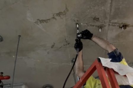 Man up a ladder working on a concrete crack injection